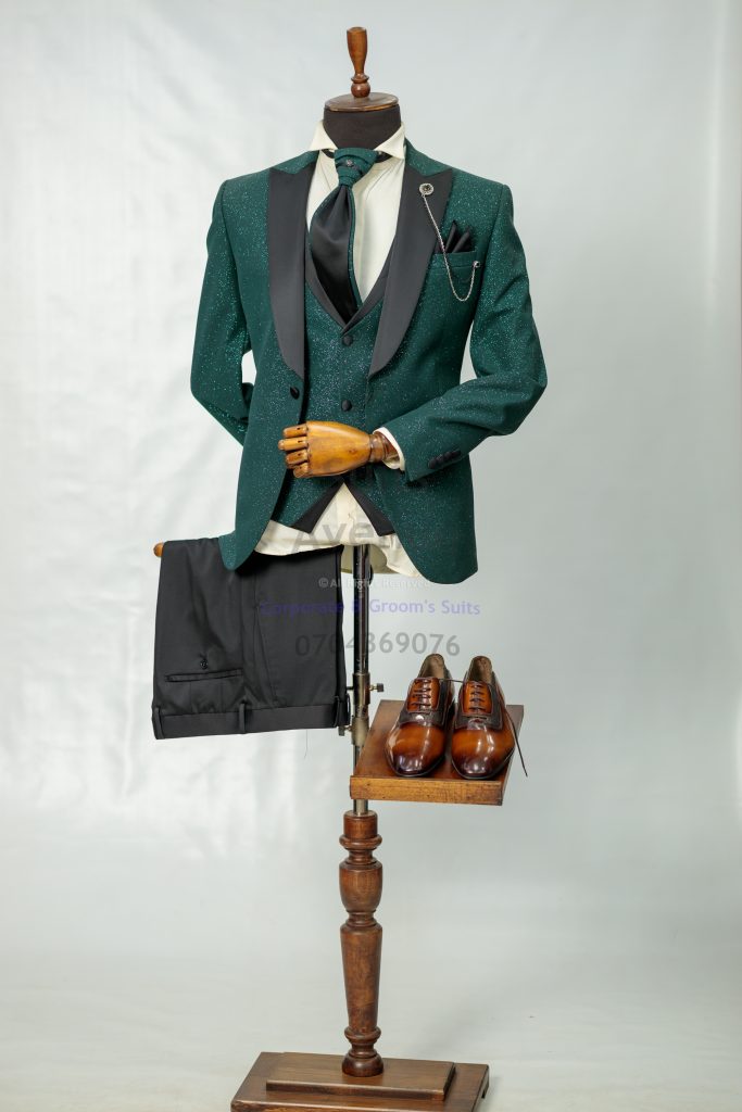 A green three-piece wedding suit on a mannequin, styled with a white shirt and bow tie